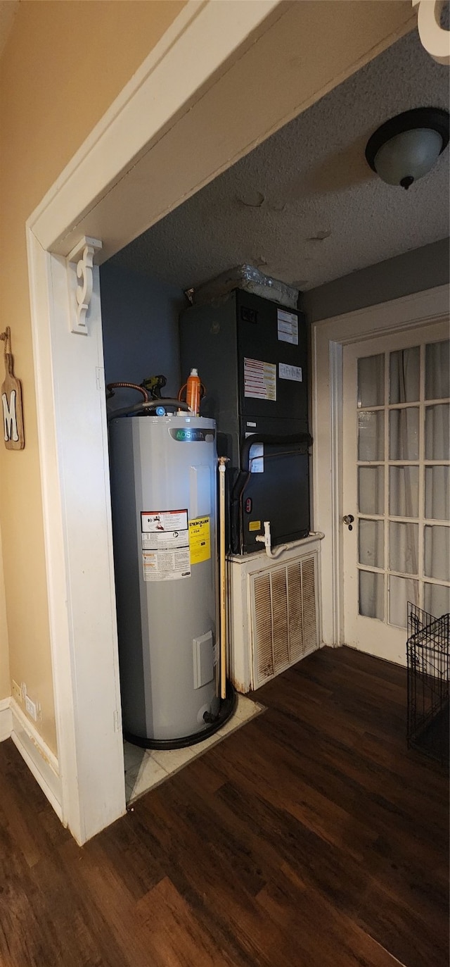 utility room featuring heating unit and electric water heater