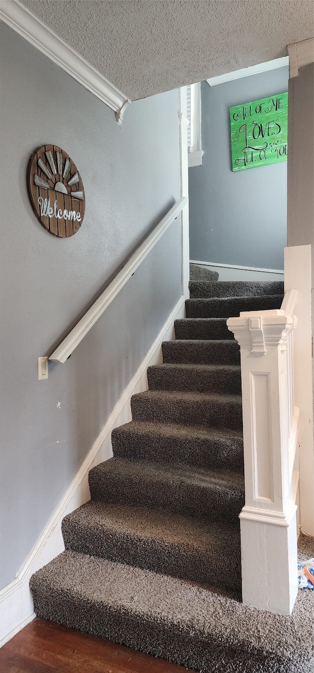 stairway featuring a textured ceiling and hardwood / wood-style floors