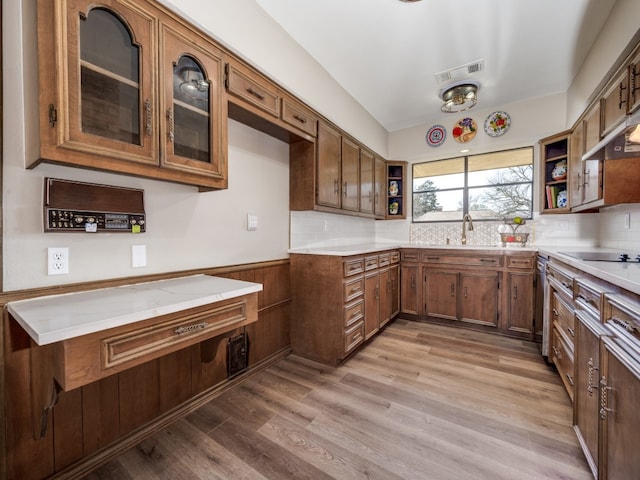 kitchen featuring black electric cooktop, backsplash, sink, and light hardwood / wood-style flooring