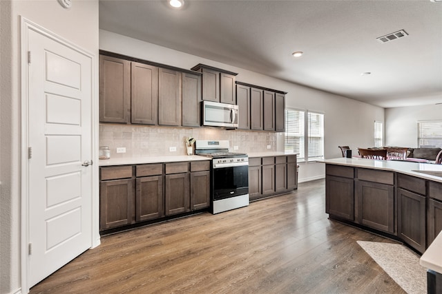 kitchen featuring white range with gas stovetop, sink, decorative backsplash, hardwood / wood-style flooring, and dark brown cabinetry