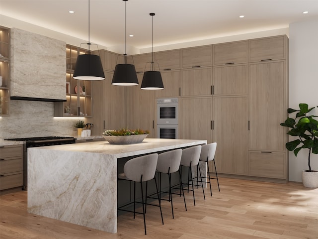 kitchen featuring light hardwood / wood-style flooring, stainless steel range oven, double oven, a kitchen island, and a breakfast bar