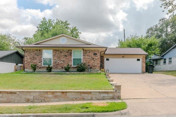 ranch-style home with a garage and a front lawn