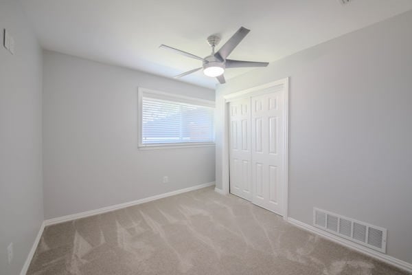 unfurnished bedroom featuring a closet, ceiling fan, and light carpet