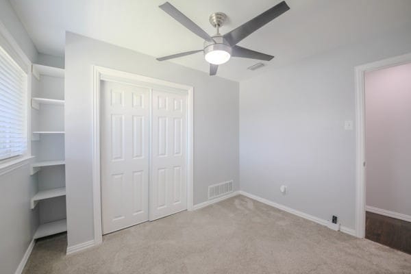 unfurnished bedroom featuring a closet, ceiling fan, and light colored carpet