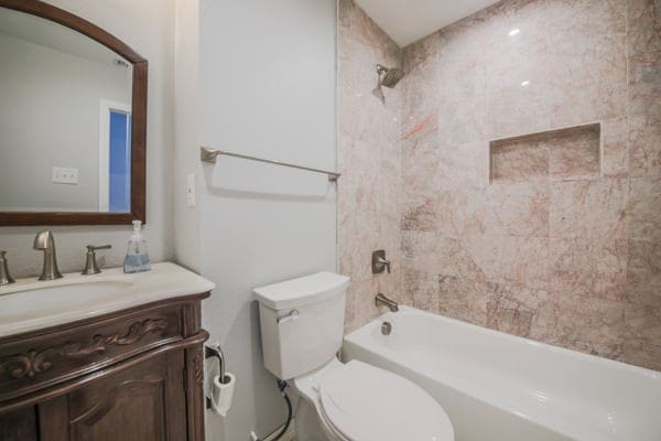 full bathroom with tiled shower / bath, vanity, and toilet