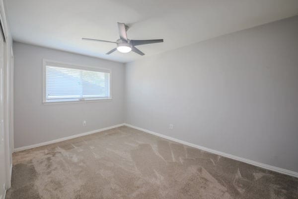 empty room with ceiling fan and carpet