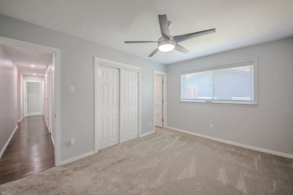 unfurnished bedroom with light carpet, a closet, and ceiling fan