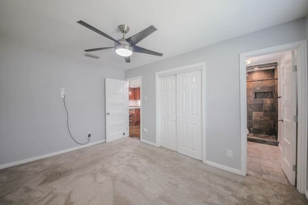 unfurnished bedroom with a closet, light colored carpet, and ceiling fan