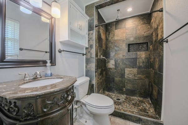 bathroom with vanity, toilet, and a tile shower