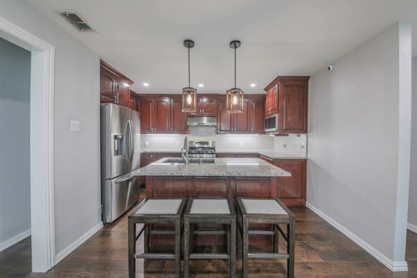 kitchen with hanging light fixtures, stainless steel appliances, sink, and dark hardwood / wood-style flooring