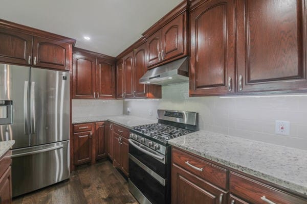 kitchen with light stone counters, stainless steel appliances, and dark hardwood / wood-style flooring