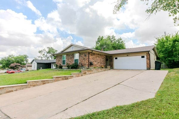 single story home featuring a front lawn and a garage