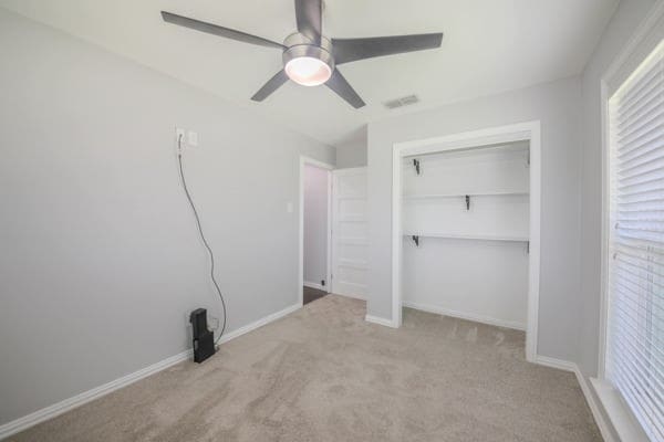 unfurnished bedroom featuring a closet, ceiling fan, and light colored carpet