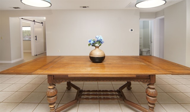 unfurnished dining area featuring a barn door and tile patterned flooring