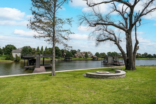 view of dock with a water view, a fire pit, and a lawn