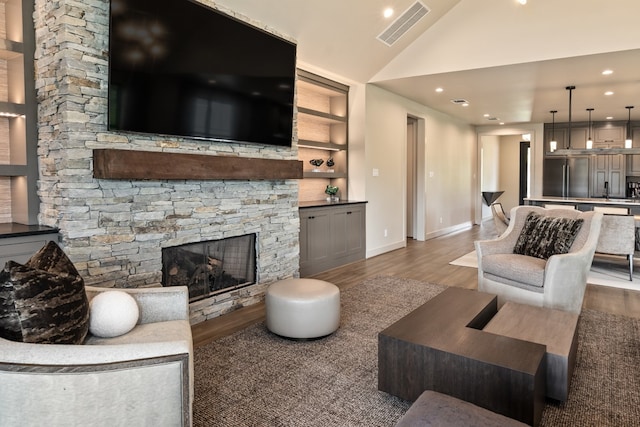 living room with built in features, dark hardwood / wood-style flooring, high vaulted ceiling, and a stone fireplace