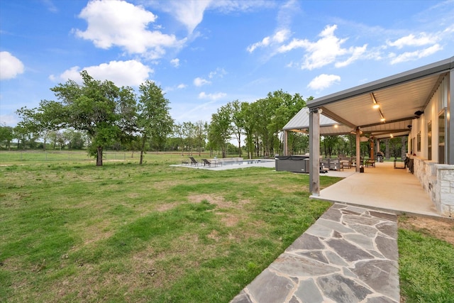 view of yard featuring a swimming pool with hot tub and a patio area