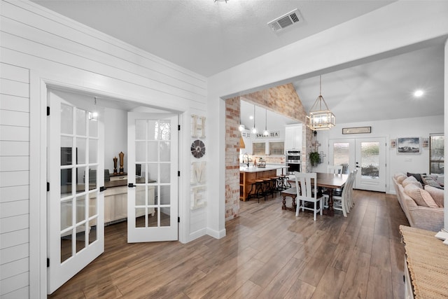 dining space with lofted ceiling, french doors, dark hardwood / wood-style floors, and a textured ceiling