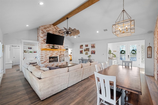 living room with ceiling fan with notable chandelier, dark wood-type flooring, french doors, vaulted ceiling with beams, and a fireplace