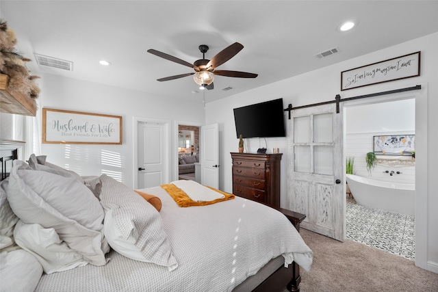 bedroom with ceiling fan, a barn door, and carpet floors