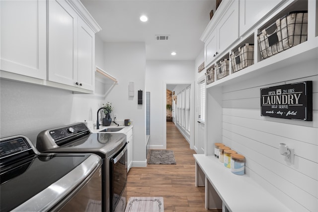 laundry room with cabinets, sink, hardwood / wood-style floors, and washer and clothes dryer