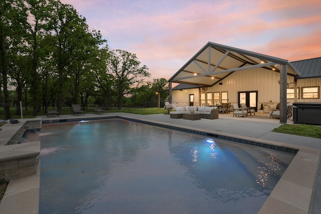 pool at dusk featuring outdoor lounge area, a hot tub, pool water feature, and a patio