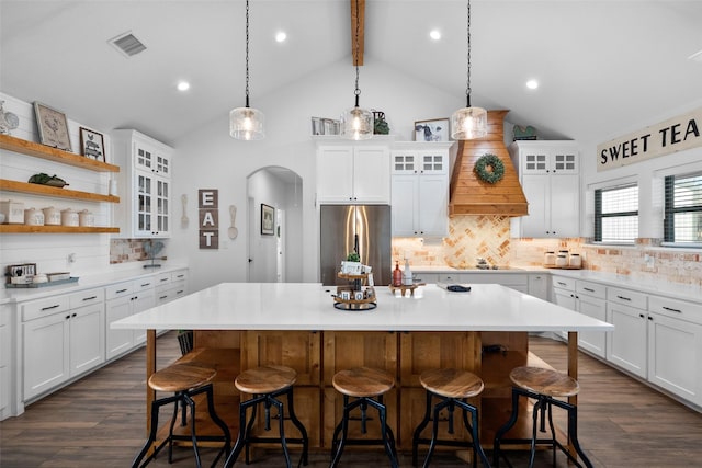 kitchen with stainless steel fridge, tasteful backsplash, a kitchen island, pendant lighting, and white cabinets