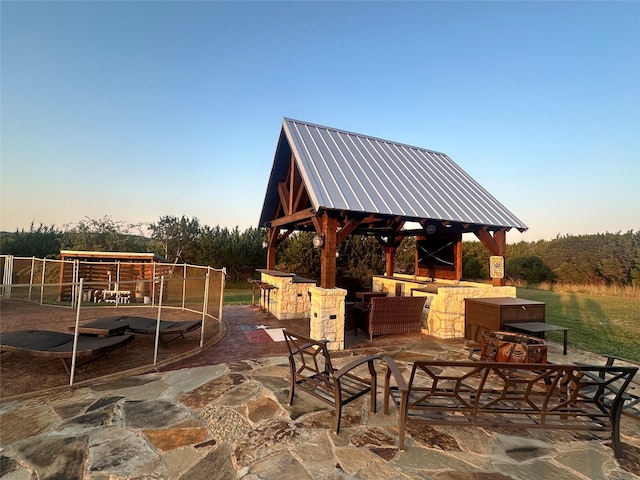 patio terrace at dusk featuring a gazebo, an outdoor hangout area, and a trampoline