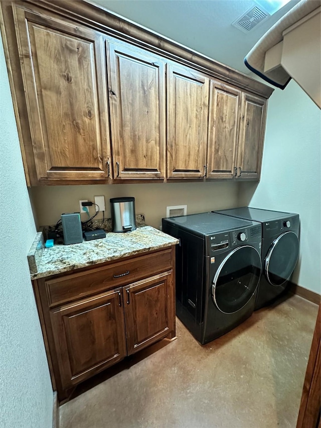 laundry area with separate washer and dryer and cabinets