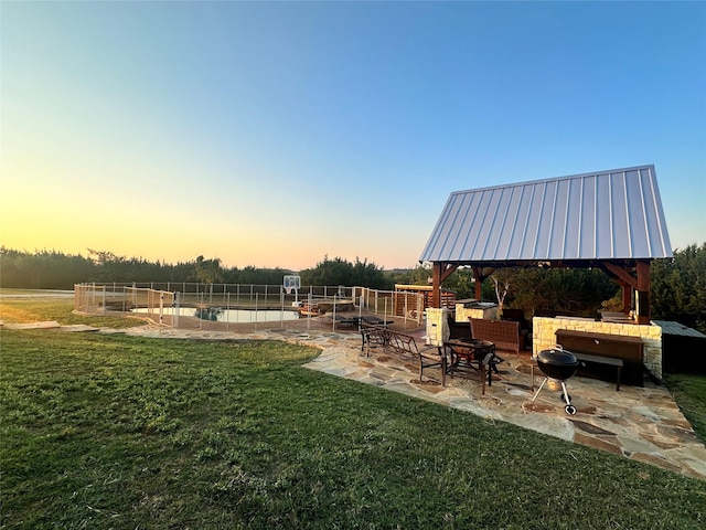 yard at dusk with a gazebo, a patio, and a fenced in pool