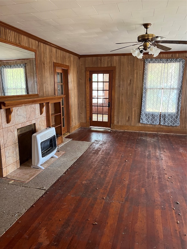 unfurnished living room featuring a fireplace, crown molding, heating unit, ceiling fan, and hardwood / wood-style flooring