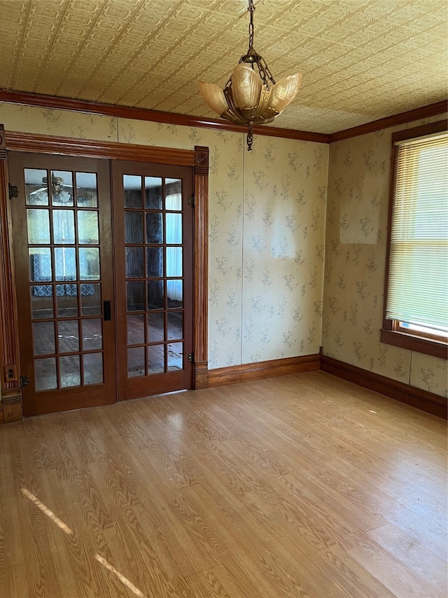 empty room featuring light wood-type flooring, french doors, and ornamental molding