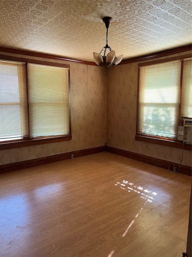 spare room with a textured ceiling, crown molding, an inviting chandelier, and light wood-type flooring