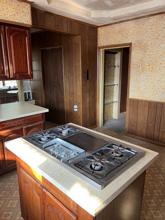 kitchen with stainless steel gas stovetop, a kitchen island, and wooden walls