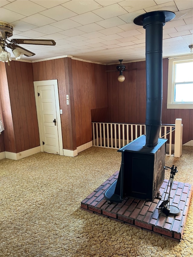 interior space featuring wood walls, carpet flooring, and a wood stove