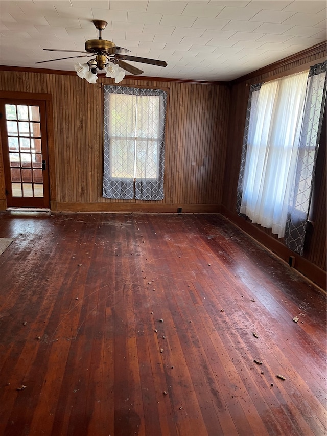 empty room featuring wood walls, ceiling fan, and dark hardwood / wood-style floors