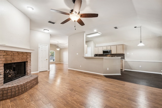 living room featuring a brick fireplace, hardwood / wood-style floors, ceiling fan, and vaulted ceiling