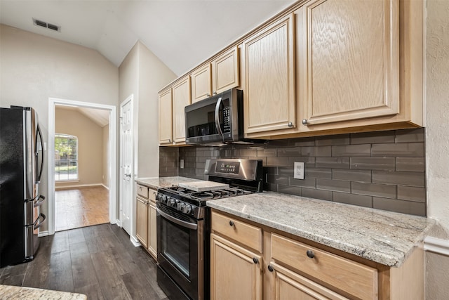 kitchen with lofted ceiling, light brown cabinets, dark wood-type flooring, appliances with stainless steel finishes, and tasteful backsplash