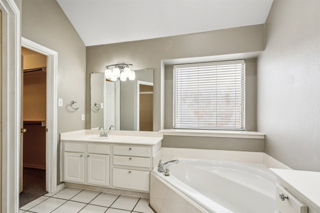 bathroom with vanity, tiled bath, vaulted ceiling, and tile patterned flooring