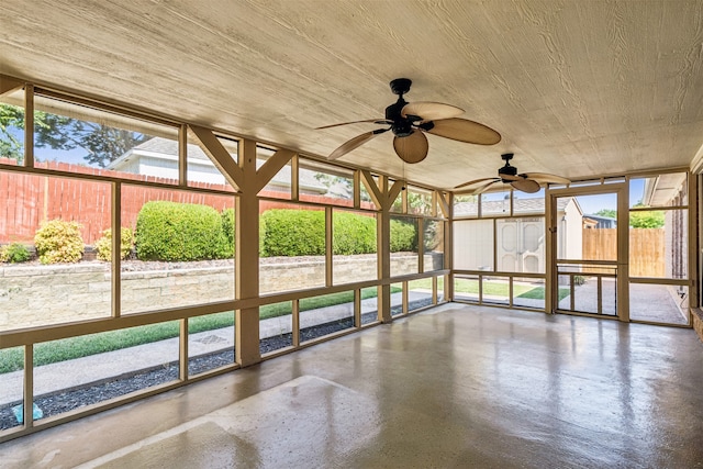 unfurnished sunroom featuring wood ceiling, a healthy amount of sunlight, and ceiling fan