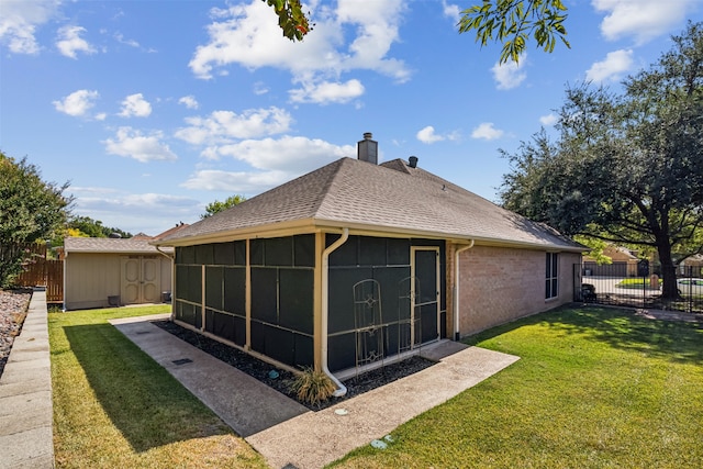 view of side of home featuring a storage unit, a yard, and a sunroom