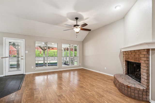 unfurnished living room with lofted ceiling, light hardwood / wood-style flooring, a brick fireplace, and ceiling fan