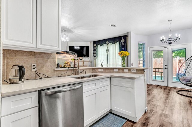 kitchen featuring light wood-type flooring, a chandelier, sink, stainless steel dishwasher, and white cabinets