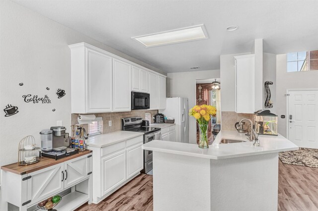 kitchen with light wood-type flooring, kitchen peninsula, sink, and electric range