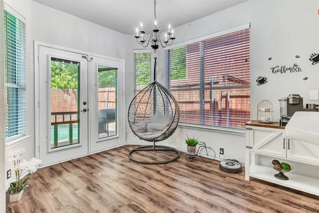 interior space featuring plenty of natural light, a notable chandelier, wood-type flooring, and french doors