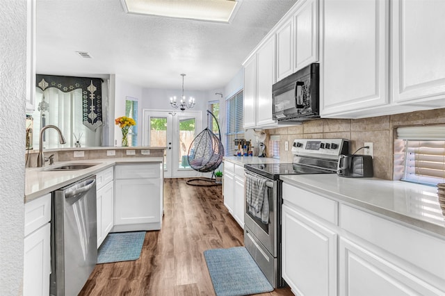 kitchen featuring white cabinets, light hardwood / wood-style flooring, appliances with stainless steel finishes, a chandelier, and sink