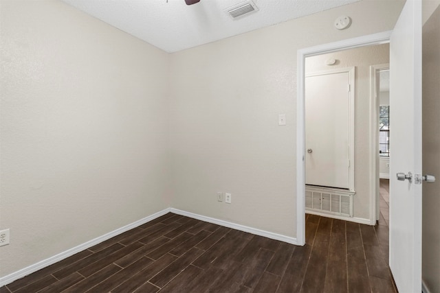 spare room featuring a textured ceiling, dark wood-type flooring, and ceiling fan