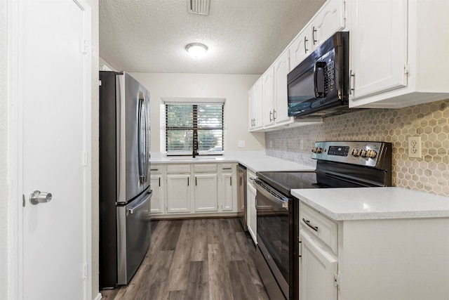 kitchen with a textured ceiling, hardwood / wood-style floors, tasteful backsplash, stainless steel appliances, and white cabinets