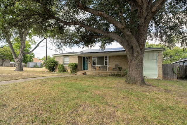 ranch-style house with a porch, solar panels, and a front yard