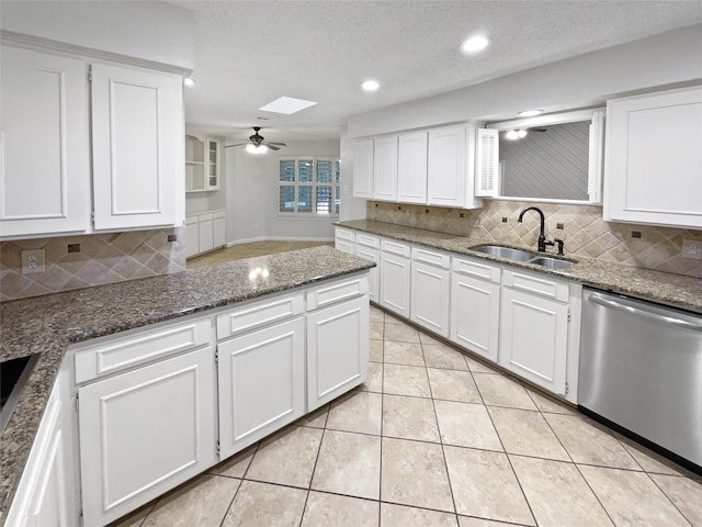 kitchen featuring stainless steel dishwasher, a ceiling fan, light tile patterned flooring, a sink, and white cabinetry